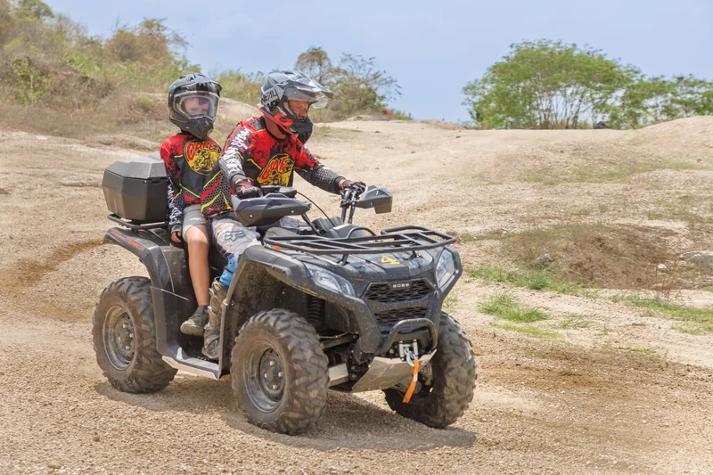 ATV carrying a rider and passenger across the trail