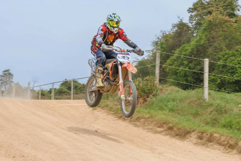 Dirt bike rider cresting a raised trail