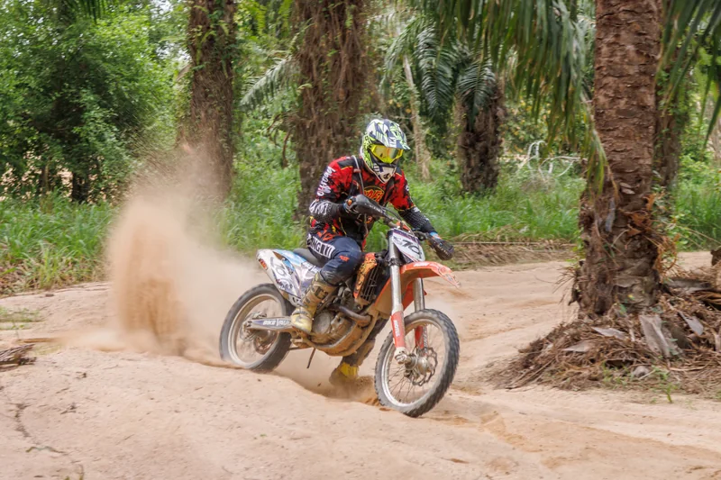 Dirt bike rider turning through sand and dust
