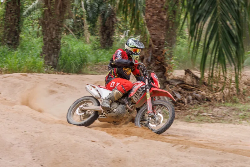 Dirt bike rider turning between palm trees