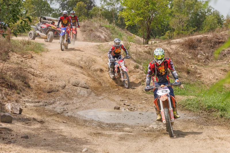Dirt bike riders descending a rocky, uneven trail