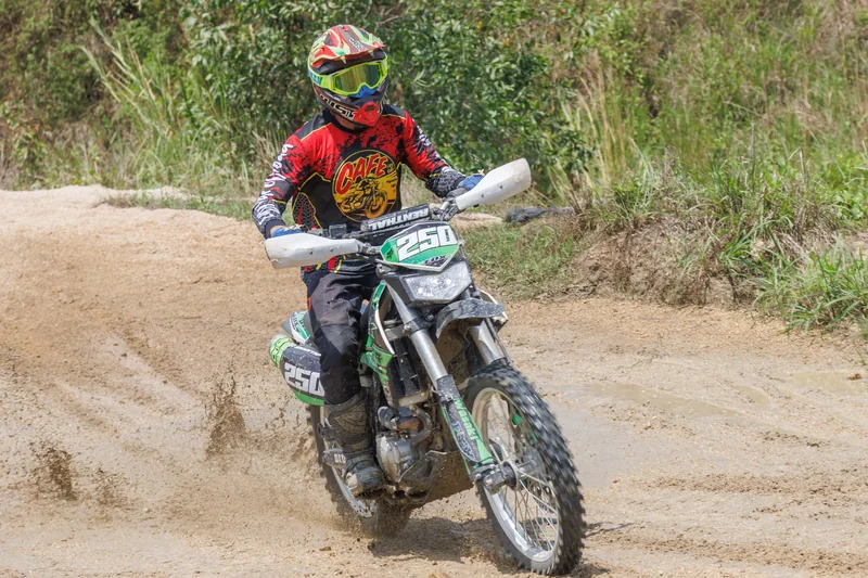 Rider guiding a dirt bike up a rocky trail