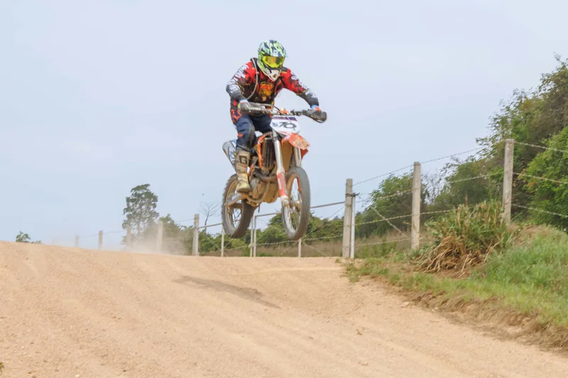 Dirt bike rider jumping from a raised sandy trail
