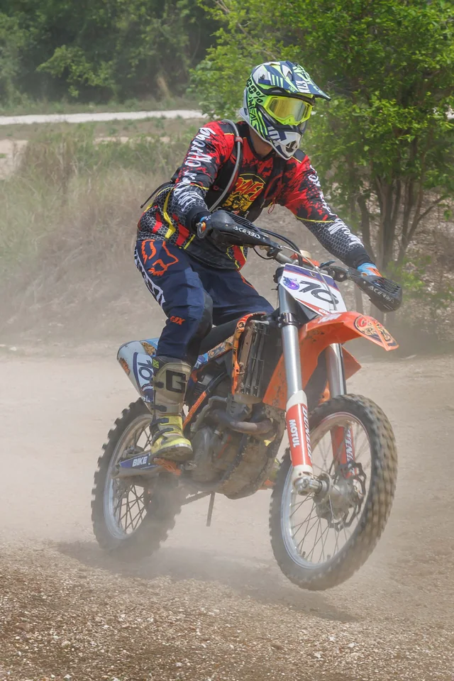 Helmeted dirt bike rider approaching on a dusty trail