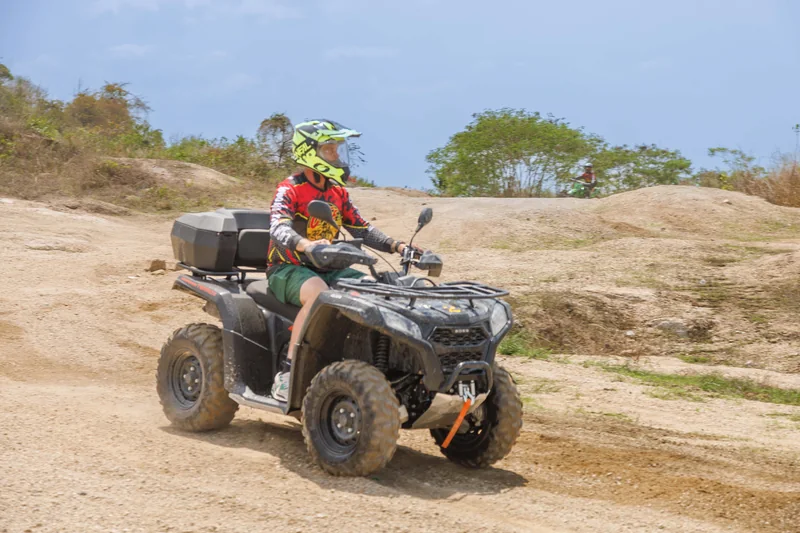 ATV rider crossing a sandy, rocky trail